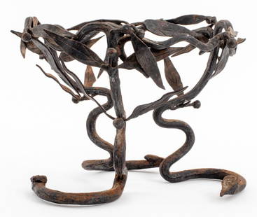 Umberto Bellotto Manner Iron Serpent Motif Stand: Umberto Bellotto (Italian, 1882-1940) manner wrought iron stand comprising three snake form legs mounted by a round laurel wreath form frame, apparently unsigned. 5.25" H x 7.25" diameter. Provenance: