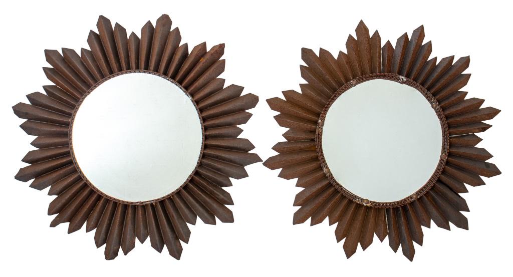 Sheet Iron Sunburst Mirrors, Pair: Sheet iron sunburst form mirrors, each centering a circular mirror plate with faceted sunburst-form frame, well-patinated with iron oxide. Mirror: 17.5" diameter; Sunburst: 30" diameter.