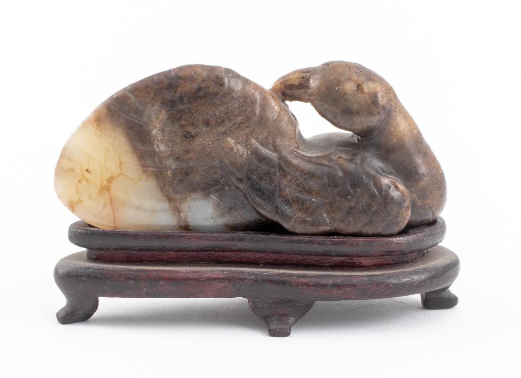 Chinese Brown Jade Carving of Recumbent Bird: Chinese brown jade sculpture depicting a recumbent bird carved with feather details, together with a fitted hardwood stand. Statue: 1.5" H x 3.25" W x 1.5" D. Provenance: Property from the Manhattan e