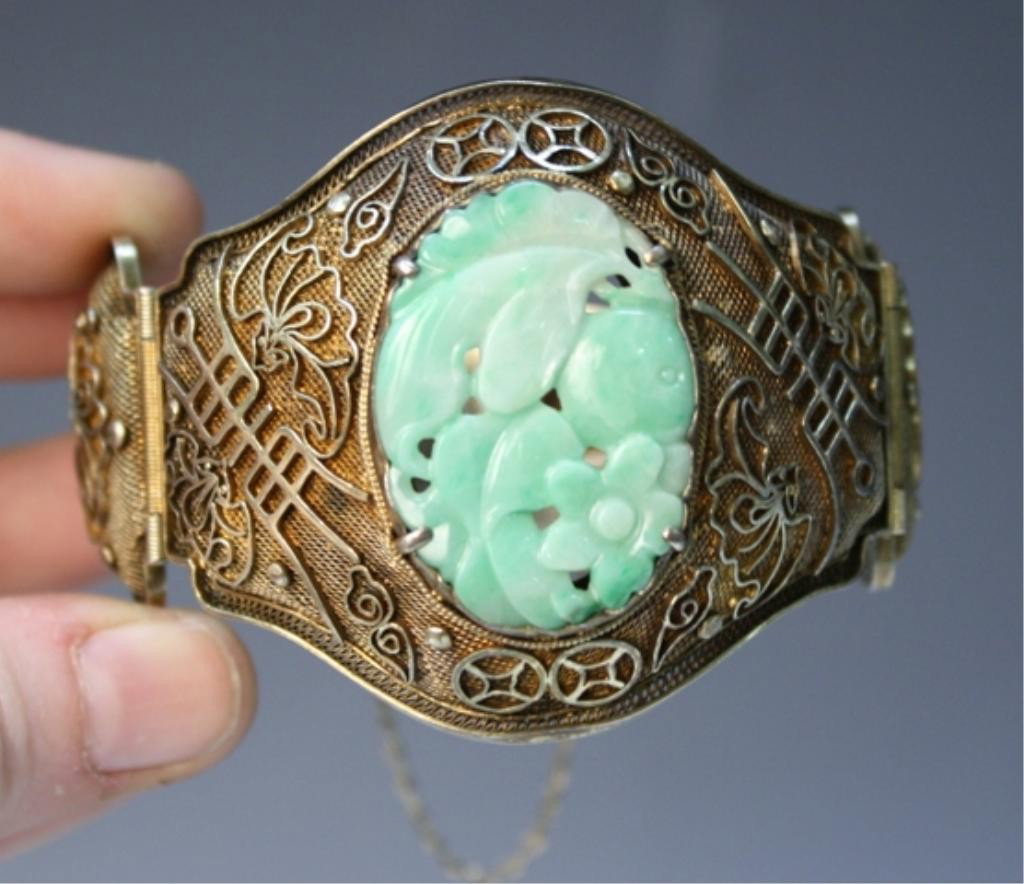 Chinese Silver Bracelet with Jade Inset: Cuff bracelet with bats and symbols of longevity, and carved inset with plants, silver and jade, China; marked SILVER on clasp. Dimensions: 2"W x 2-1/4" diameter of interior