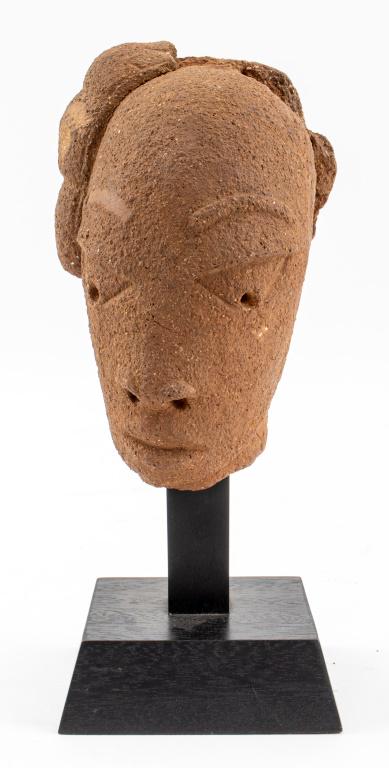Ancient African Nok Terracotta Head of an Elder: Ancient Western African Nok culture terracotta sculpture depicting the head of an elder figure, together with an ebonized wood stand. Some losses to figure's coiffure. 10.5" H x 4.5" W x 4.5" D overal