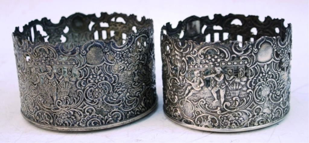 Chatillon Co. Pair Sterling Silver Bottle Bases: Pair of sterling bottle bases with figural scenes and other designs, New York, United States, twentieth century; marked "Sterling" and "Brand-Chatillon." Dimensions: larger one is 3"H x 4-1/2" diamete