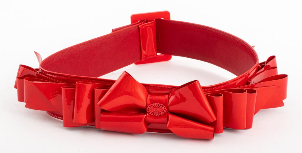 Chanel Red Leather & Vinyl Belt: Chanel red vinyl belt, red leather interior marked "Chanel - Made in Italy" and "cuir veritable", having bow motif to outside with double-C logo, size "70/28". 30.75" H x 3" W. Provenance: Property fr