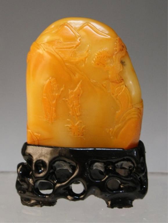 Chinese Small Soapstone Carving with Stand: Small carving with figures in a landscape, soapstone with wood stand, China; unmarked. Dimensions: stone approximately 2"H x 1-1/2"W x 1/2"D; with stand 2-3/4"H x 2"W x 1"D