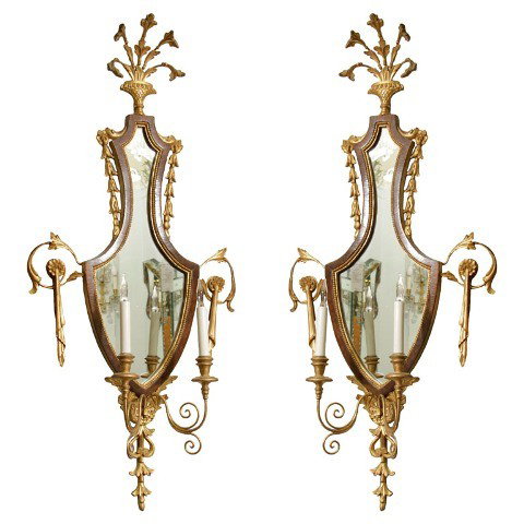 French Art Deco Mirrored Candelabra Sconce Pair: A pair of art deco sconces, each with a mirrored back and two candle form lights detailed with scrolling vegetal brass work, France, c 1930s; unmarked. Dimensions: each 41"H x 19"W x 7"D