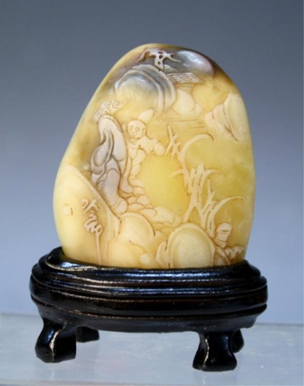Chinese Small Soapstone Carving: Small carved soapstone boulder with figural scene and wood stand, China; unmarked. Dimensions: with stand2-5/8"H x 2"W x 1-1/4"D; without stand 2"H x 1-3/4"W x 7/8"D