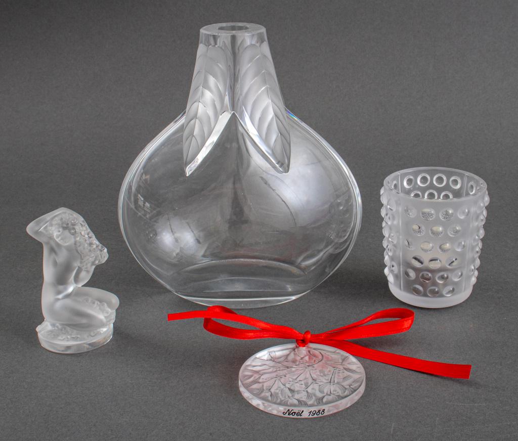 Lalique Frosted Crystal Table Article, 4: Lalique assembled group of four frosted crystal articles comprising (1) one bottle vase with leaf motifs, (1) one candle holder, (1) one nude lady paperweight and (1) one Christmas ornament marked "No