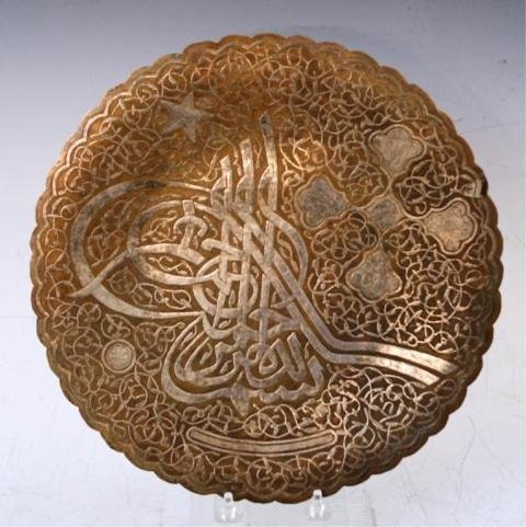 Turkish Bronze Decorative Plate w/ Tughra: Bronze decorative plate with tughra of Suleyman the Magnificent and surrounding patterns, has three feet and hook for wall mounting; unmarked. Dimensions: 1/4"H x 11-3/4" diameter