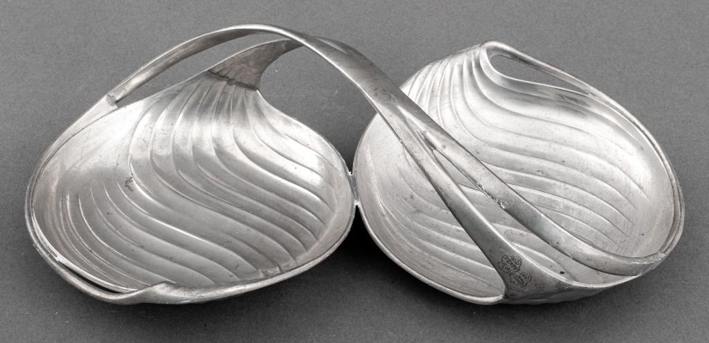 Christofle Art Nouveau "Canna" Coupe, ca. 1900: Christofle Art Nouveau period silverplated tin "Canna" coupe with two dishes conjoined by a swirling handle, struck "ETAIN / Pavillon / Christofle" to handle. 3.5" H x 13.25" W x 6.5" D.
