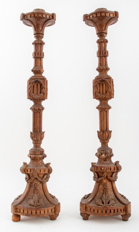 Neoclassical Wooden Pricket Sticks, Pair: Pair of Neoclassical wooden pricket sticks, each with circular tops with dentel moldings above wreath-carved supports, on garlanded circular bases upon three toupie feet. 30" H x 7.25" diameter.