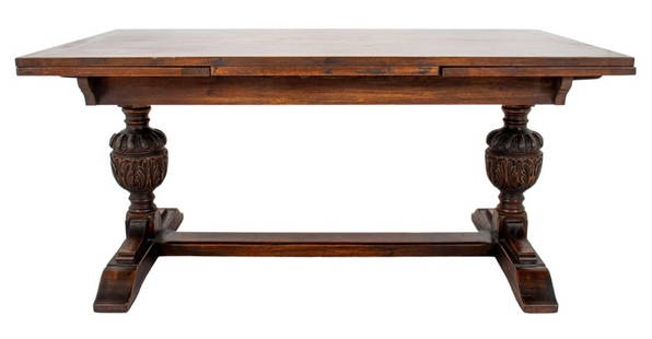 Tudor Revival Oak Dining Table: Tudor Revival carved oak wood dining table with two acanthus leaf design urn-form supports, with two leaves. Closed: 30.5" H x 66" W x 38" D. Provenance: Property from a 239 Central Park West estate.