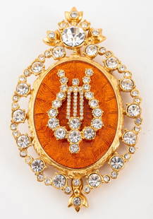 Christian Dior Gem-Set Guilloche Brooch Pendant: Christian Dior designer costume jewelry gold-tone metal pin pendant mounted with colorless rhinestone crystals encircling a central orange guilloche medallion surmounted by a gem-set harp, marked "Chr