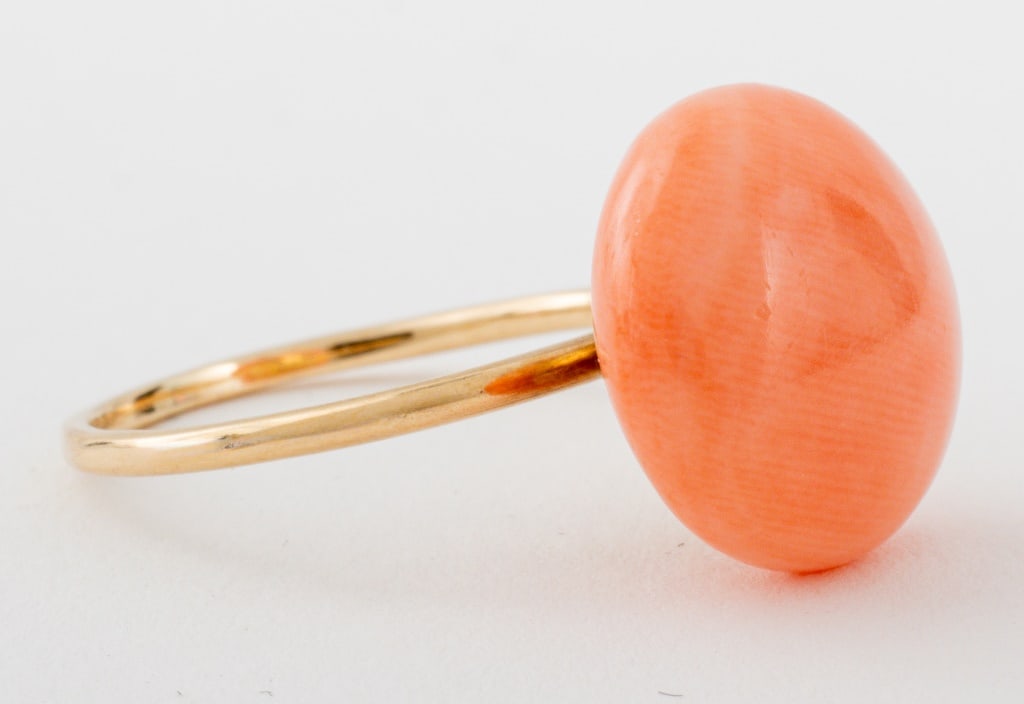 14K Yellow Gold Coral Ring: 14K yellow gold ring, brightly polished, featuring a solitaire coral cabochon. Gold tested. Measuring US size 4 1/2, approx. 12 mm across widest point, approx. 1.5 dwt.