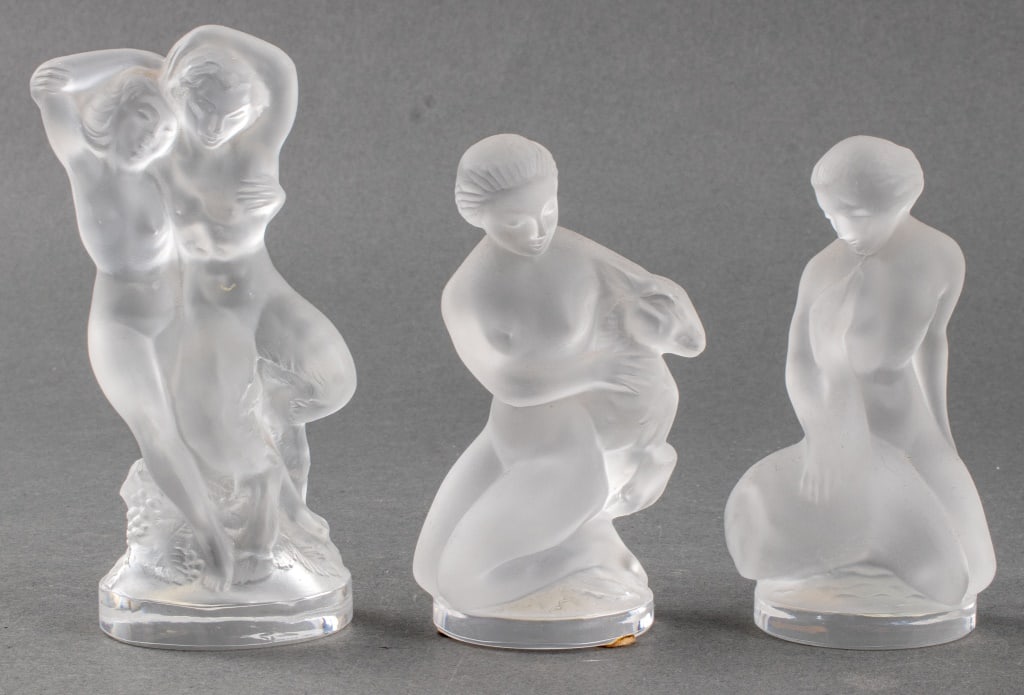 Lalique France Nude Women Crystal Figurines, 3: Three Lalique France crystal glass sculptures of nude women, one with a swan, one with a lamp, and one of a couple, marked "Lalique / France." 5.5" H x 2.5" W x 2" D.