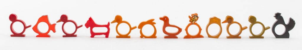 Vintage Bakelite Animal Form Napkin Rings, 12: Group lot of vintage Bakelite napkin rings, five in the form of birds (two with beaks lacking) in butterscotch, green, and red, one black Bakelite rooster, one clear red Bakelite fish, one Donald duck