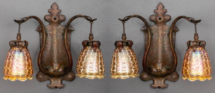 Arts & Crafts Bronze Sconces with Quezal Shades, 2: Pair of Arts and Crafts bronze two arm wall sconces with Quezal iridescent gold-tone art glass shades, the mountings with hammered finish and stylized foliate design, shades signed. 14" H x 15" W x 8"