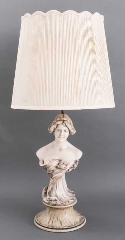 Royal Dux Bohemia Porcelain Woman Bust Lamp: Royal Dux Bohemia porcelain sculpture depicting the bust of a young woman mounted as a lamp. Statue: 16" H x 8.5" W x 7" D; lamp: 36.5" H x 16" diameter.