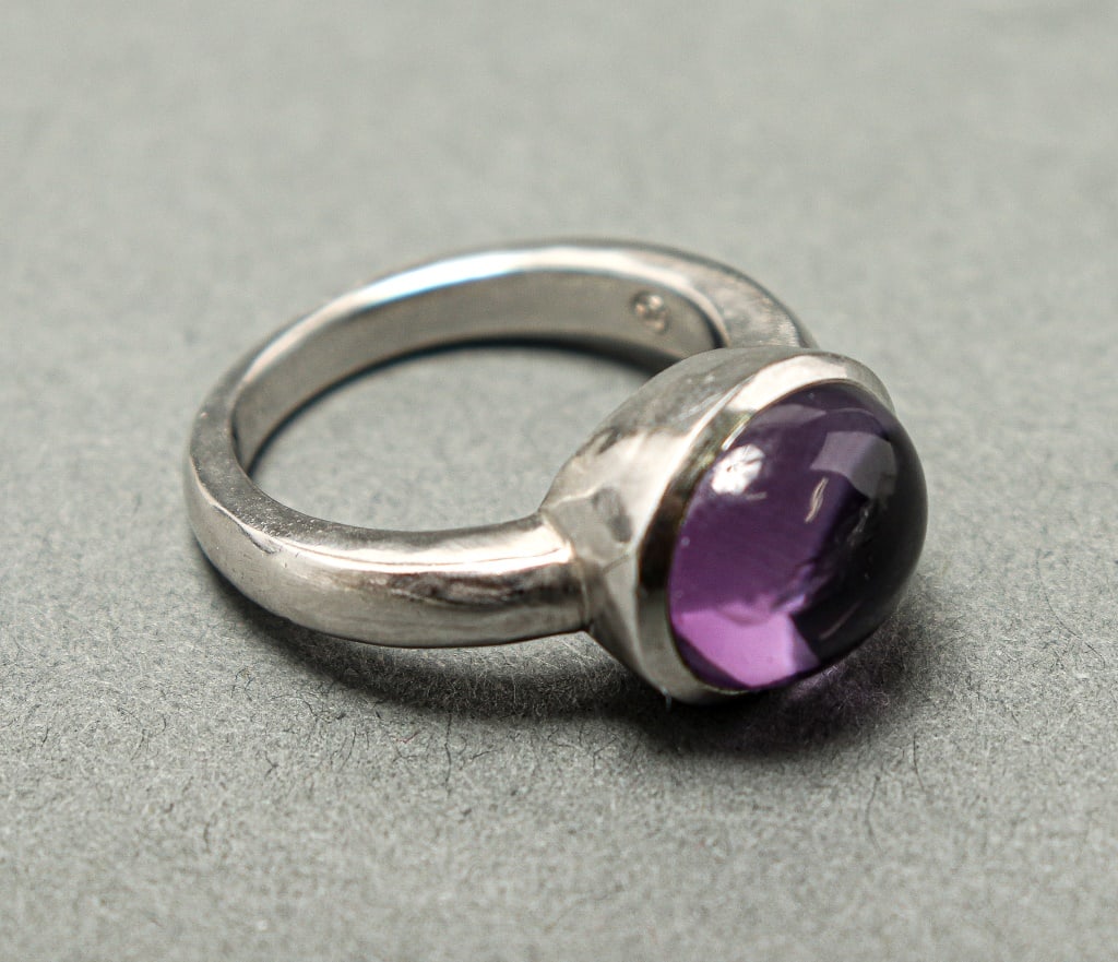 Movado Silver Amethyst Ring: Movado silver amethyst ring, 0.875" L x 0.5" W x 0.375" H; stamped: "925", maker's mark "M". Ring size: 6 3/4. Approx. 0.24 ozt. inclusive.