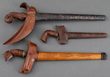 Antique Indonesian Kris Daggers, 3: Three antique Indonesian kris knives with hand-carved wood handles, one with silver scabbard with repousse floral decoration, one with carved wood scabbard, and one with incised decoration to the stee