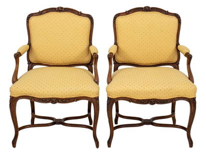 French Louis XV Style Upholstered Oak Armchair, 2: Pair of French Louis XV Style Carved Oak Arm Chairs, each with floral crest above a shaped rectangular upholstered back raised on cabriole legs joined by X stretchers with floral motif, now upholstere