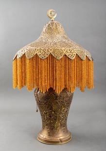 Syrian Pierced Brass Table Lamp, ca. 1920s: Syrian Pierced Brass Table Lamp, circa 1920s, the shade struck "MADE IN SYRIA", with amber-tone beaded fringe and surmounted by crescent moon and star form finial. 24.5" H x 17" Diameter. Provenance: