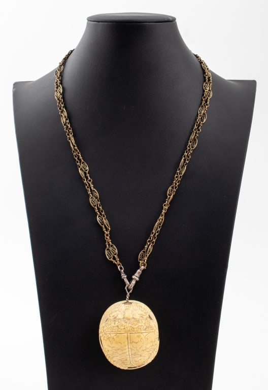 Egyptian Revival Carved Bone Scarab Amulet: Egyptian Revival Carved Bone Scarab Amulet, circa early 20th century, hieroglyphs to reverse, on a brass chain with sterling silver clasps marked with assay hallmarks. Pendant: 2.25" L x 2" W x 1" D.