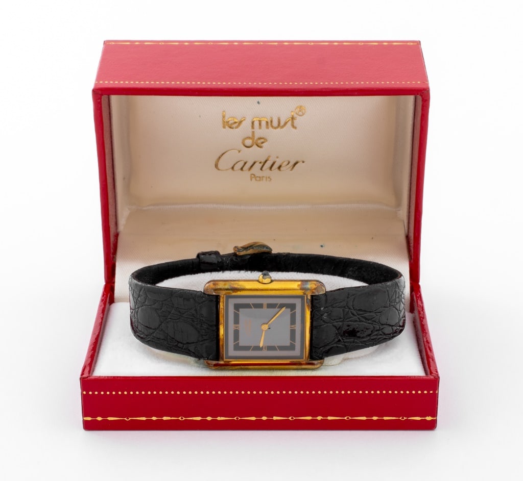 Cartier Vermeil Tank Watch: Cartier Vermeil Tank Watch, featuring grey dial with golden Roman numeral indexes, powered by battery operated quartz movement, worn with leather strap and buckle closure, marked: "must de Cartier Swi