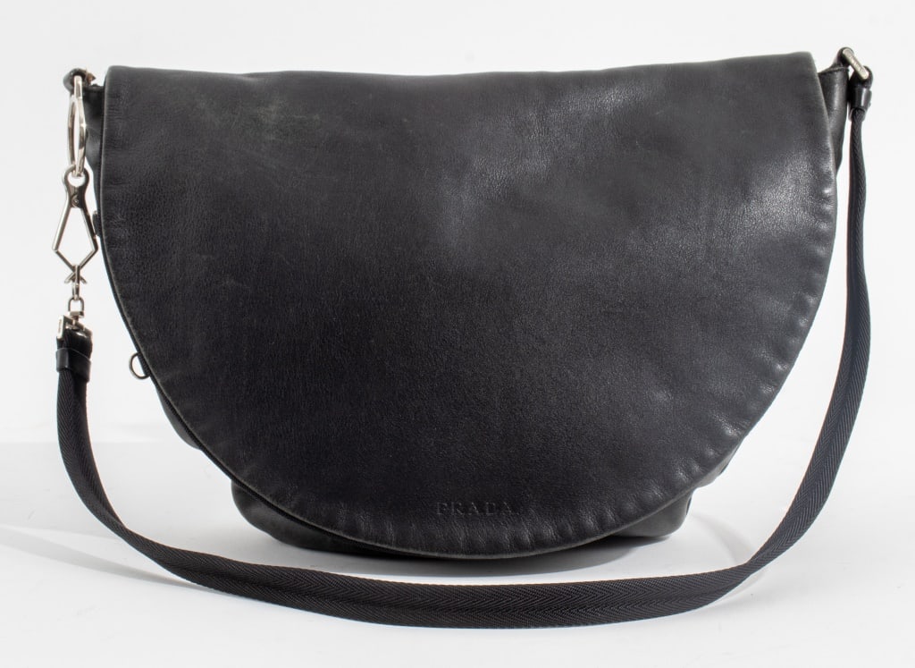 Prada Black Leather Shoulder Bag: Prada Black Leather Shoulder Bag with flap, black nylon strap and interior, marked "PRADA" to front flap and labeled "PRADA / MILANO / MADE IN ITALY" with cotton Prada dust bag. Overall: 26" L x 15.5"