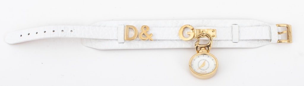 Dolce & Gabbana White Leather Bracelet: Dolce and Gabbana White Leather Bracelet, with gold-tone logo and clip-on timepiece, stamped "D&G / Dolce & Gabbana" to underside 8.75" L x 2" W. Provenance: From a New York City Collection. Keywords: