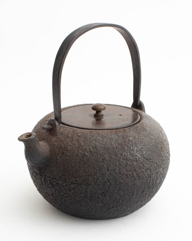 Japanese Cast Iron Tetsubin Teapot: Japanese Cast Iron Tetsubin Teapot, with bronze lid, iron swing handle, inscribed to underside of lid. 7.75" H x 6.75" W x 6" D. Provenance: From a 333 East 75th Street Estate. Keywords: Tea kettle, K
