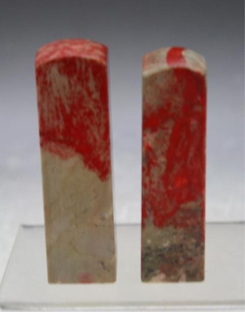 Chinese Lot of 2 Carved Jixue Stone Seals: Set of two carved seals with mottled red and grey color, jixue (chicken blood) soapstone, China; unmarked. Dimensions: Larger 3-1/2"H x 1" square; smaller 3-3/8"H x 7/8" square