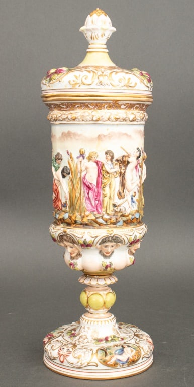 Capodimonte Porcelain Covered Urn: Capodimonte Porcelain Covered Urn, 19th century, with a Bacchanalia scene in relief, blue underglaze mark to underside. 15.25" H x 5" Diameter. Provenance: From a New York City Collection. Keywords: N