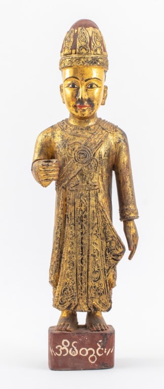 Burmese Carved Gilt Wood Nat Spirit Sculpture: Burmese Carved Giltwood Nat Spirit Sculpture, the figure standing upright upon a red painted base with white writing, his right hand open, likely once holding a sword. 23" H x 7.5" W x 6" D. Provenanc