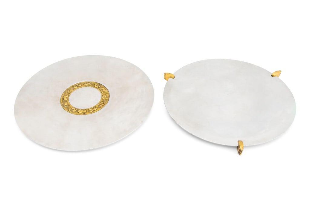 Kensington, Inc. Mixed Metal Chargers, 2: Two Kensington, Inc. Aluminum and Brass Chargers, one designed by Lurelle Guild (American, 1898-1985) with Zodiac motif, marked with stag above a shield with a K inside, and one with three brass Art D