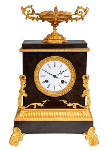 Charles X Gilt and Patinated Bronze Mantel Clock: Charles X Gilt and Patinated Bronze Mantel Clock, circa 1830, with a circular enamel dial, the movement strike on bell, surmounted by a two handle tazza, acanthus scrolled mounts, and rectangular plin