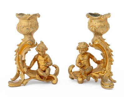 Putti Motif Gilt Bronze Candlesticks, Pair: Pair of Putti Motif Gilt Bronze Candlesticks, probably 19th century and French, cast with scrolling foliate designs. 4.5" H x 4" W x 3.5" D. Provenance: From a Palm Beach Collection. Keywords: Lightin