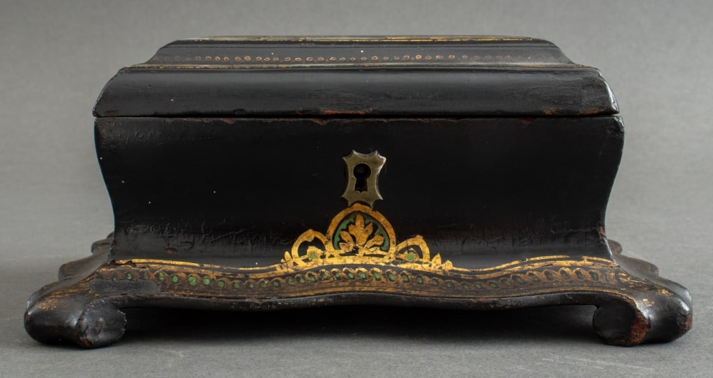 Victorian Shell-Inlaid Papier Mache Casket, 1870s: Victorian Shell-Inlaid Papier Mache Casket, 1870s, with hinged lid centering a shield shaped shell inlay, above a canted casket form body, on a shaped plinth with gilt tracery decoration. 3.5" H x 7.2