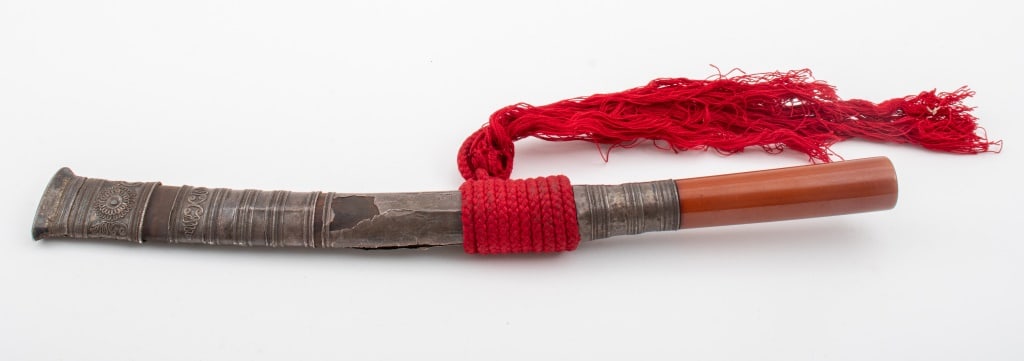 Indo-Persian Silver Handled Dagger: Indo Persian Silver Handled Dagger, the silver sheath decorated with spirals, swirls, and geometric designs, and mounted with a red braid. 15.25" L x 13" W to tassel. Provenance: From a New York City