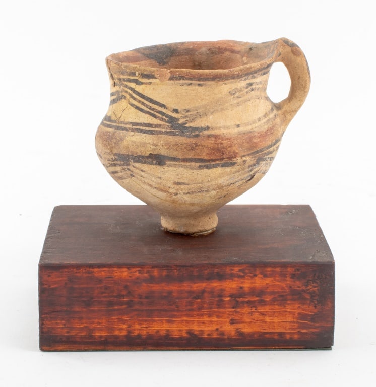 Chinese Neolithic Pottery Handled Cup: Ancient Chinese Neolithic Pottery Hand-Painted Redware Handled Cup, with white and black geometric decoration, mounted on a hardwood stand. 5.25" H x 5.25" W x 3.75" W. Provenance: From a New York Cit