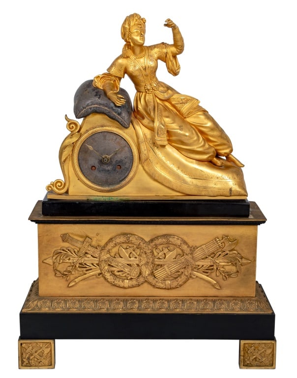 French Empire Gilt Metal and Marble Figural Clock: French Empire Gilt Metal and Black Marble Figural Clock, surmounted by a seated woman in Turkish costume, resting on a pillow, the clock with later battery mechanism, on an associated gilt metal stand