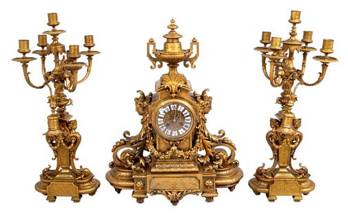 Napoleon III Gilt Bronze Three-Piece Clock Set: Napoleon III Gilt Bronze Three-Piece Clock Set, circa 1870, comprising: a clock surmounted by two-handled urn with a circular dial inset with enameled numerals, with acanthus scrolls, figural supports