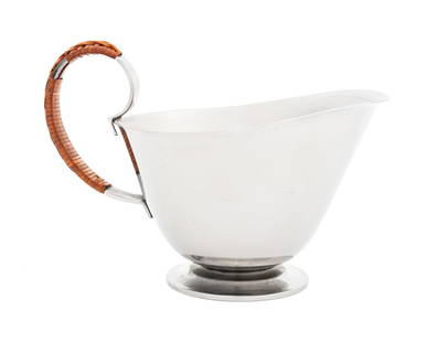 Georg Jensen Stainless Steel Footed Pitcher: Georg Jensen Stainless Steel Footed Pitcher, with rattan wrapped handle, marked "Georg Jensen Stainless / Made in Denmark / 5" to the underside. 5.5" H x 7" W x 4.5" D. Provenance: The Upper East Side