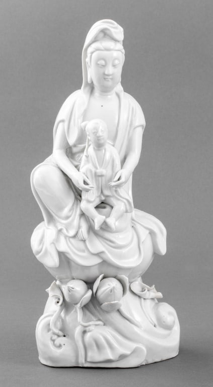Chinese Blanc de Chine Porcelain Guanyin: Chinese Blanc de Chine Dehua Porcelain Guan Yin Sculpture, with acolyte seated on lotus flower. 10.5" H x 4.75" W x 3.75" D. Provenance: From an East Village Estate. Keywords: Statue, Ceramics, White