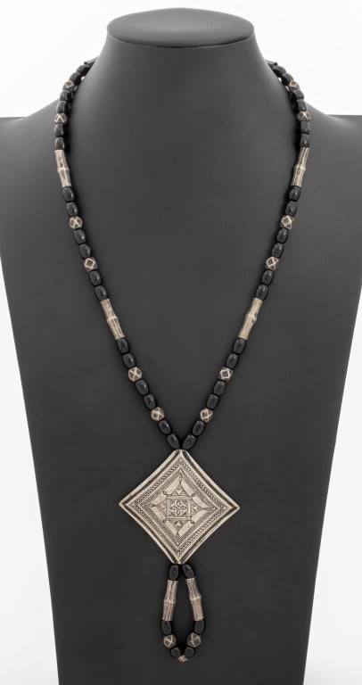 Tribal Tuareq Silver Black Stone Bead Necklace: Tribal Tuareq Ornate Silver Black Stone Bead Square Engraved Shield Drop Necklace. Drop shield measures 4.5" L x 2.56" W. Necklace: 24.0" L x 0.25" W. Silver tested. Approx: 2.74 ozt. inclusive. Prove