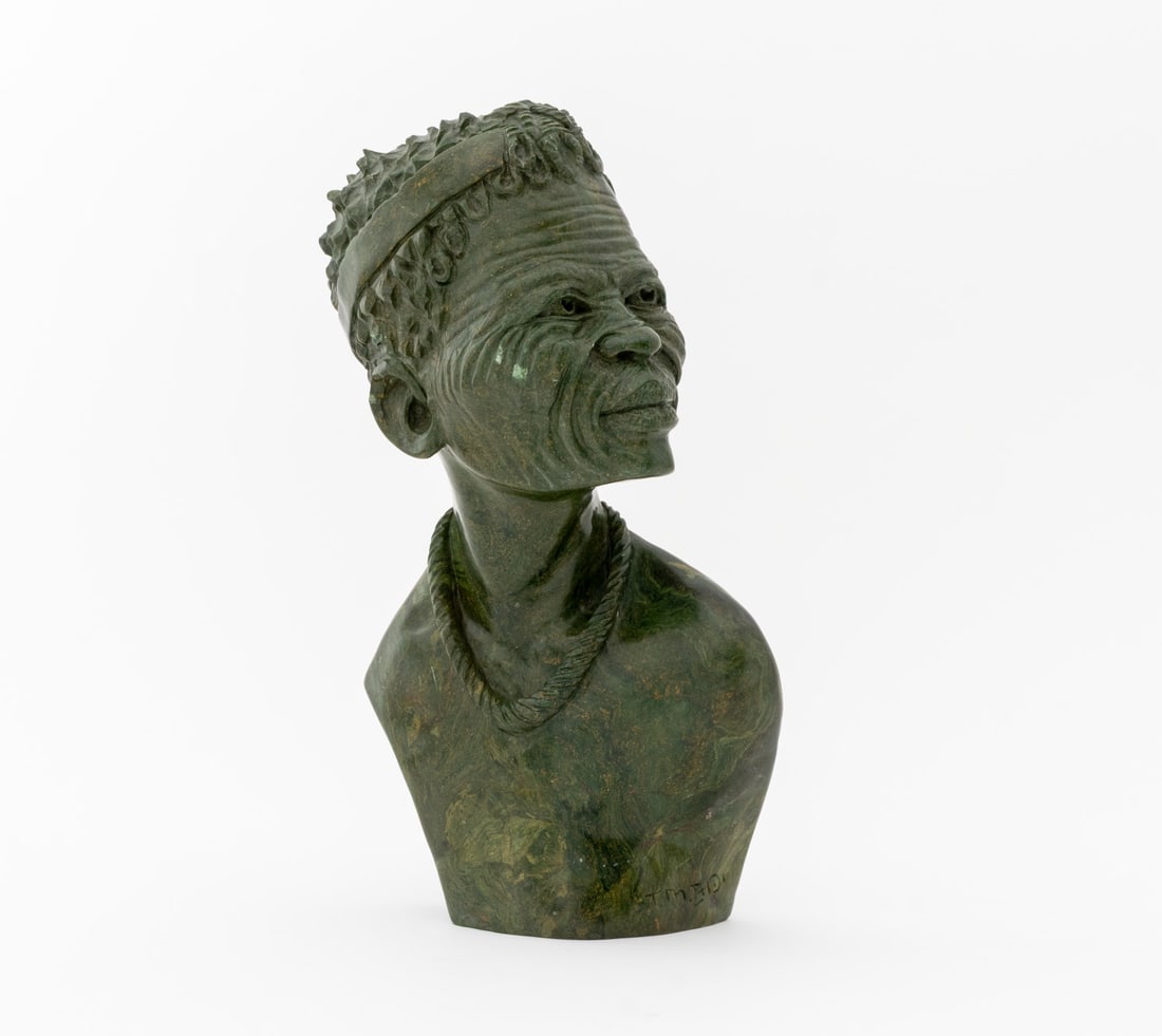 T.M. Gidi Shona Male Bust Verdite Stone Sculpture: T.M. Gidi (Zimbabwe, b. 1954) Shona Male Bust Verdite Stone Sculpture, signed lower right. 12" H x 6.5" W x 5.5" D. Provenance: From an 880 Fifth Avenue Collection. Keywords: Statue, Portraiture, Port