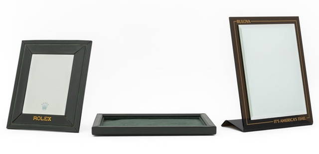 Rolex, Etc. Advertising Articles, 3: Collection of Three Advertising Articles, comprising: Bulova counter top beveled mirror on smoky plastic stand, marked "It's America's Time.", Rolex green leather wrapped table top beveled mirror, and