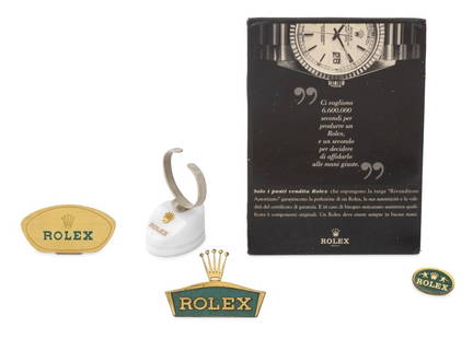 Rolex Advertising and Display Articles, 5: Collection of Five Rolex Genuine Advertising and Display Articles, comprising: watch display stand with white marble base and gold-tone crown emblem, two patinated metal signs, gold-tone and acrylic o