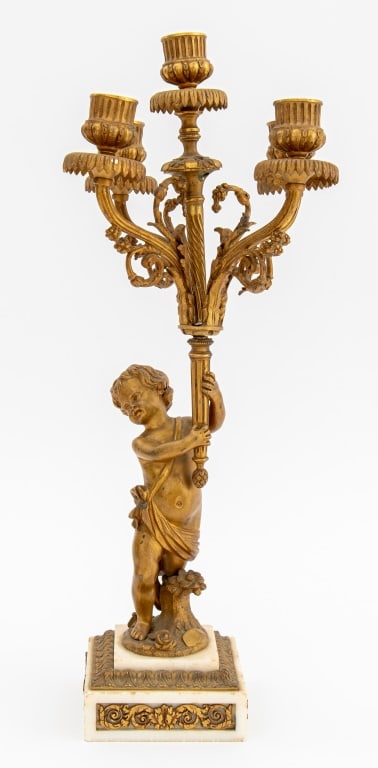 French Empire Style Gilt Bronze Cupid Candelabra: French Empire Style Gilt Bronze Cupid Candelabra, cupid upholding five branch torch, on square marble plinth with inset foliate bronze friezes. 18" H x 8.5" W x 8.5" D. Keywords: Lighting, Antiques, P