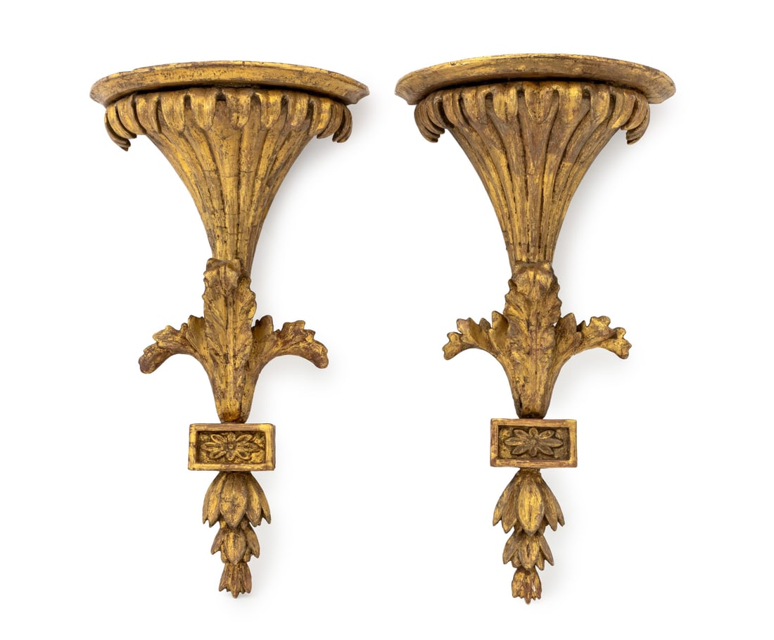 George III Giltwood Wall Brackets, Pair: Pair of George III Giltwood Wall Brackets, early 19th century, each with demilune top above fluted foliate forms, foliage, and floral rosette detail. 18.75" H x 10" W x 6.5" D. Provenance: Florian Pap