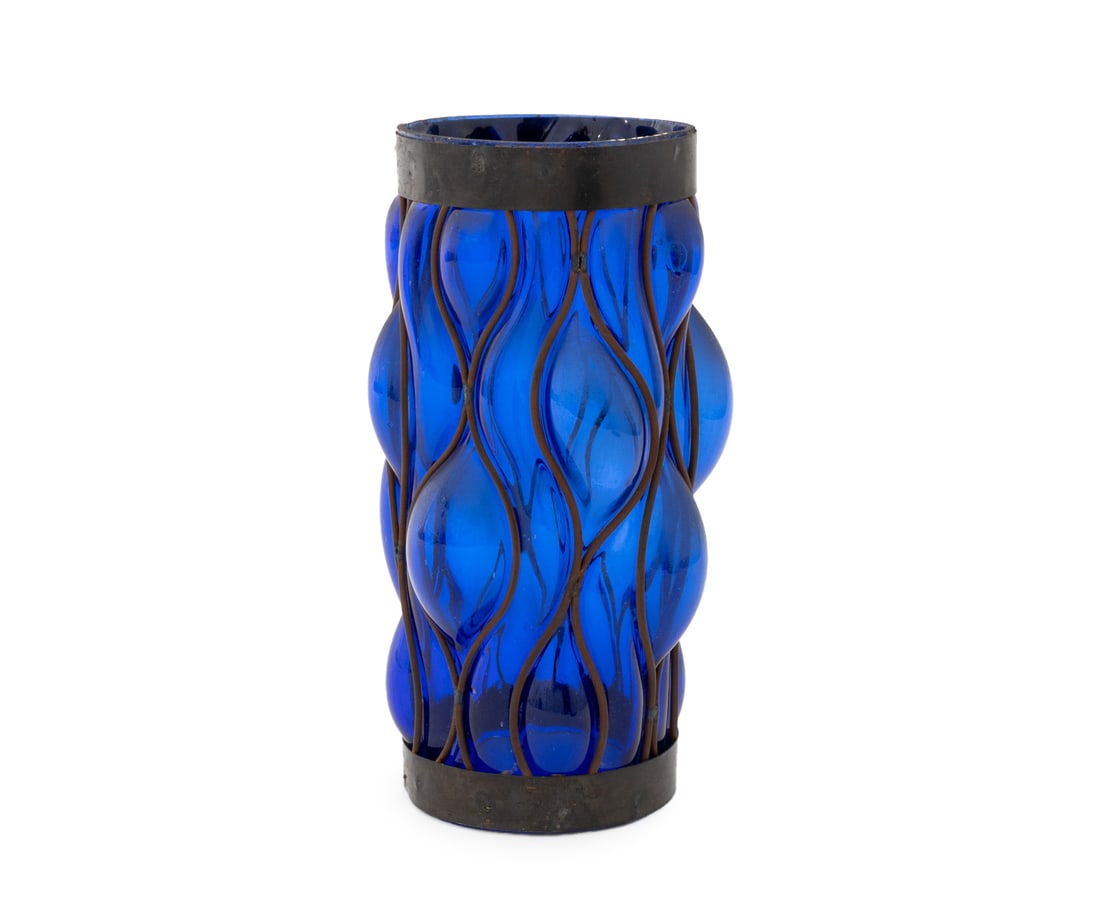 Brutalist Caged Cobalt Blue Glass Lantern: Brutalist Wrought Iron Caged Cobalt Blue Glass Lantern, the cylindrical form with openings to top and bottom. 9" H x 4.5" Diameter. Provenance: From a New York City Collection. Keywords: Imprisoned Gl